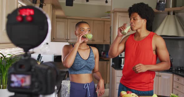 Two diverse male and female friends making culinary video blog in kitchen