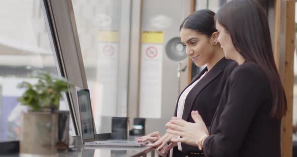 Two Business Women Standing in Front of the Window of a Restaurant Where They Ate Before