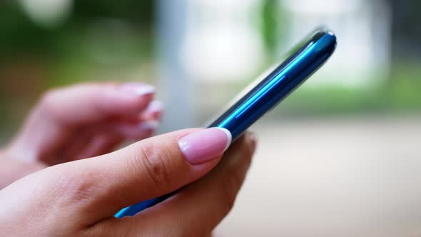 A woman is sitting in a cafe with a smartphone in her hands with a green screen mockup.