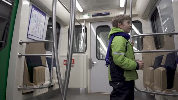 Funny Caucasian boy 5 years old in winter clothes rides in an empty subway car
