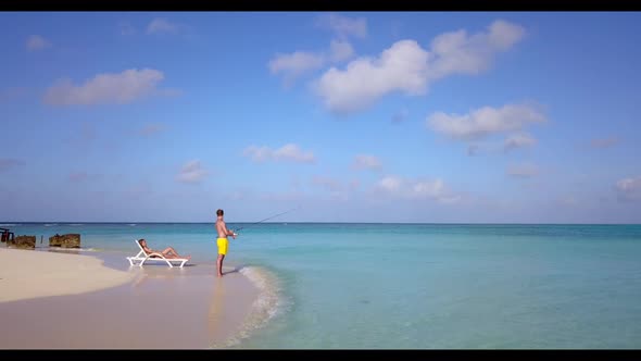 Man and woman sunbathing on exotic sea view beach time by blue green water with bright sandy backgro