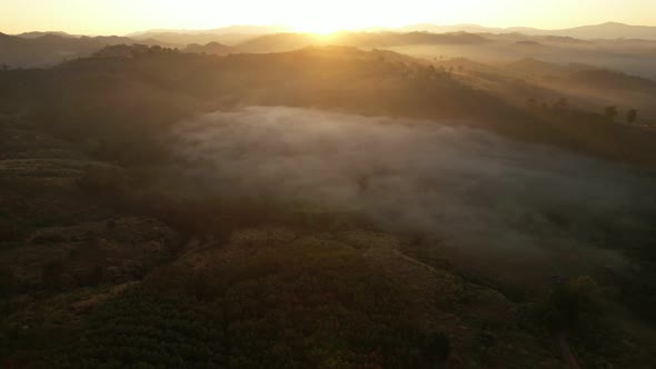 4K aerial view over a misty mountainous area. The great golden sun in the morning