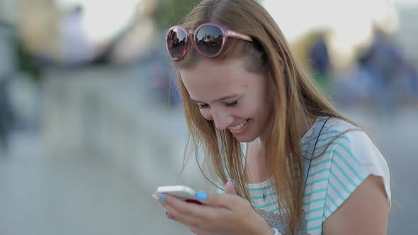 Happy Girl Using a Smart Phone in a City Embankment Sitting