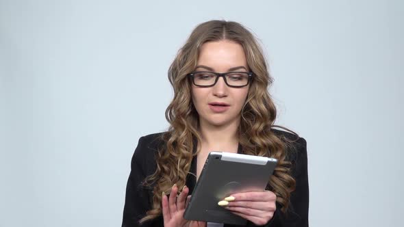 Pensive Businesswoman Texting on Her Tablet with Smile on Gray Background in Studio, Slow Motion