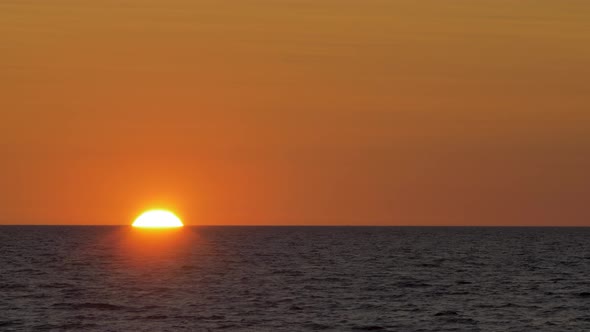 Romantic sunset over the calm Baltic sea, big red Sun sets over the horizon in summer, medium shot f