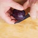 A man clumsily cuts large juicy plums in half with a knife. Very large dark blue plums - VideoHive Item for Sale