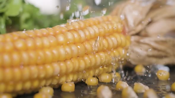 Water Falling And Splashing On Yellow Corn With Pieces Of Corn Kernels. - closeup, slow motion