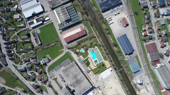 Top down aerial view over a swiss city with a river and an outdoor pool.