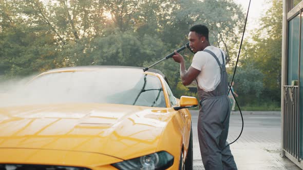 Handsome African Guy in Tshirt and Protective Overalls Washing His Yellow Luxury