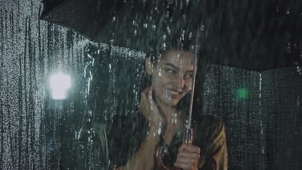 Flirting Look at Camera of Happy Girl with Umbrella Under Night Heavy Rain