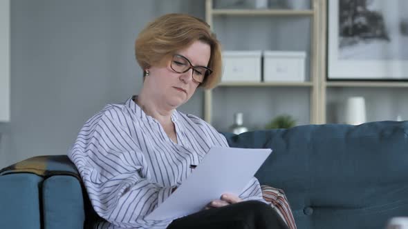 Old Senior Woman Writing on Documents While Sitting on Sofa Paperwork