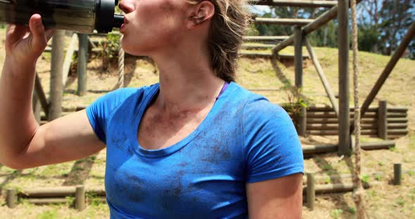 Fit woman drinking water after workout during obstacle course