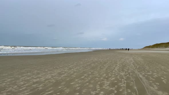 Slow motion pov walk on sandy beach during ebb tide of North Sea during dark day in Germany