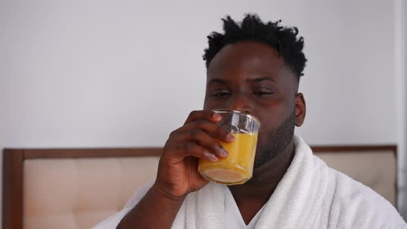 Portrait of Young Handsome African American Man Drinking Orange Juice in the Morning Looking Up