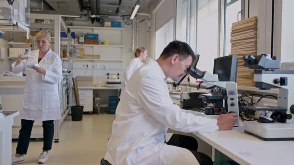 Scientist looking through microscope in laboratory