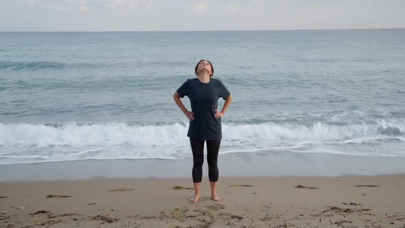 Mature Woman Doing Morning Exercises on the Beach