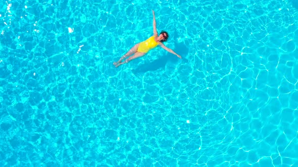 View From the Top As a Woman in a Yellow Swimsuit Lying on Her Back in the Pool
