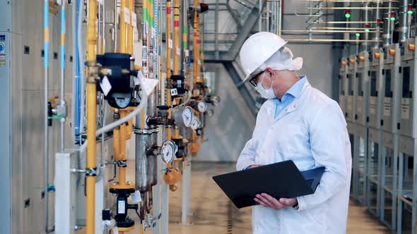 Male Inspector with a Laptop is Observing Plant Pipes