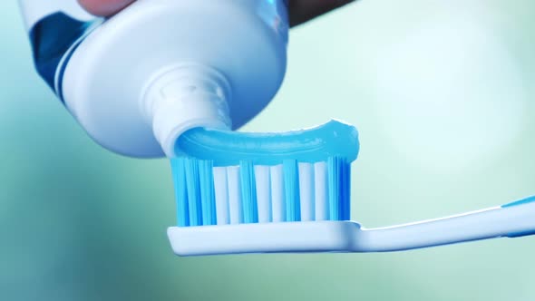 Dental Health - Squeezing Blue Toothpaste From a Tube Onto a Toothbrush.