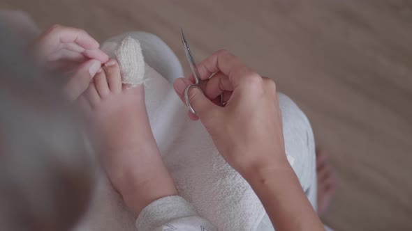 Mother Bandages Her Child's Big Toe and Cuts Nails on Other Foot