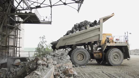 Heavy Dump Trucks Belaz Unload Granite Stones on the Granite Crushing Line Slow Motion