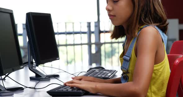 Schoolgirl using computer in classroom