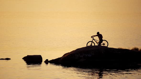 Sportive man with bicycle at sunset. Man with a bike enjoys the view of sunset