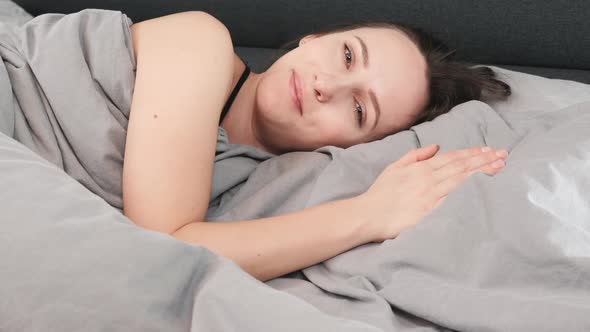 Woman waking up and looking at camera, close up. 