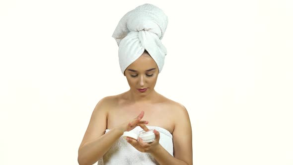 Portrait of Young Woman in White Towel on Her Head Applying a Cream on Her Previously Cleansed Face