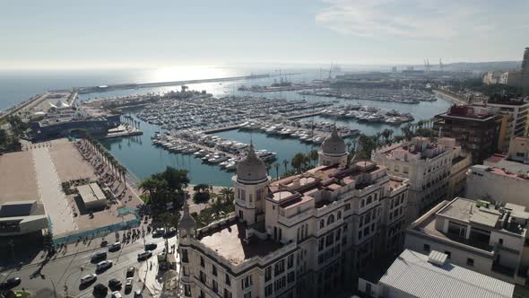 Aerial forward view with orbit descending over a magnificent building and behind the marina with boa