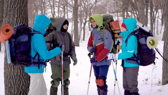 Young Tourists Are Wearing Warm Jackets and Holding Backpacks, Chatting and Discussing in Winter