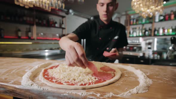 Handsome Pizzaiolo Adding Sausage on Pizza Base