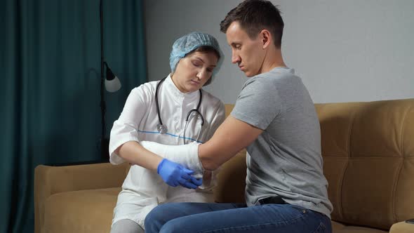 Lady Nurse Uses Swathe to Bandage Broken Arm of Young Man