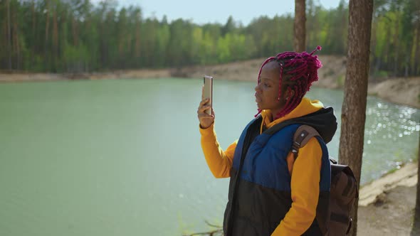 A Young Black Woman Hiking in the Woods on a Background of Mountains