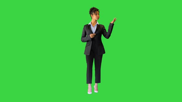 Young Black Woman in a Suit Pointing at Blank Spaces on a Green Screen Chroma Key