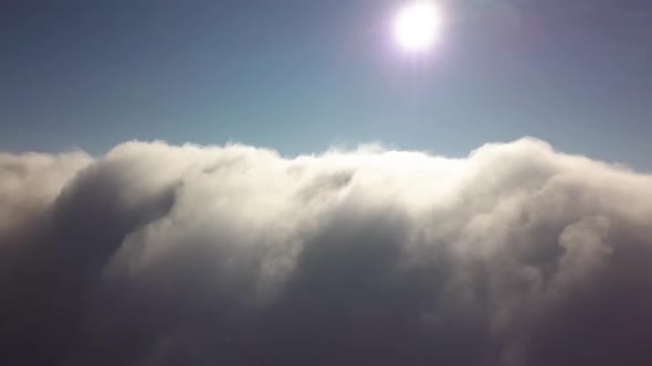 Reveal shot of aerial view from above of white puffy clouds. alt
