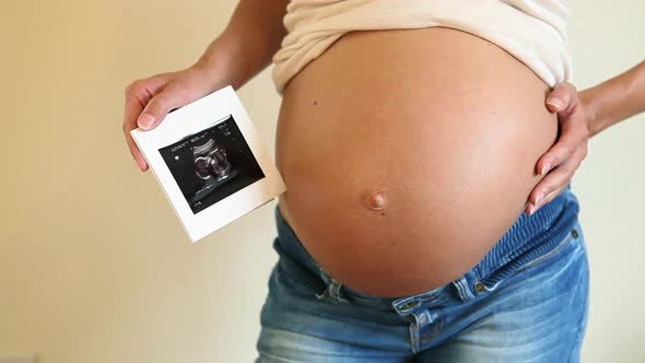 Pregnant woman showing baby bump and baby scan