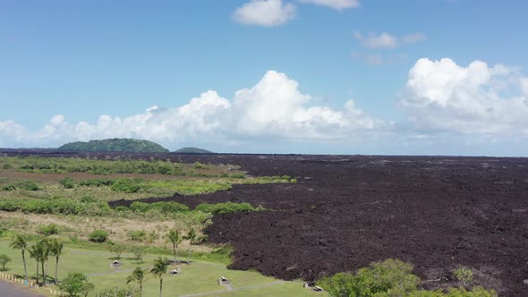 Aerial rising wide shot of a recently dried lava flow cutting through the rainforest on the Big Isla