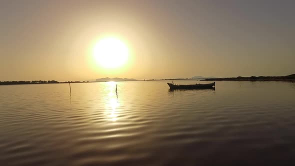 Aerial view of a lake and old boat at sunset.