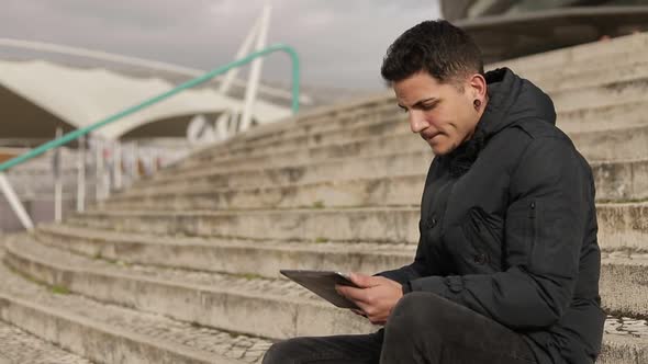 Concentrated Young Freelancer Working with Tablet Outdoor