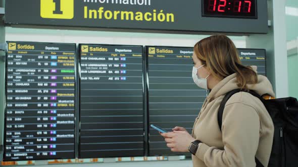 Woman Watching Arrival Board and Checking Flight