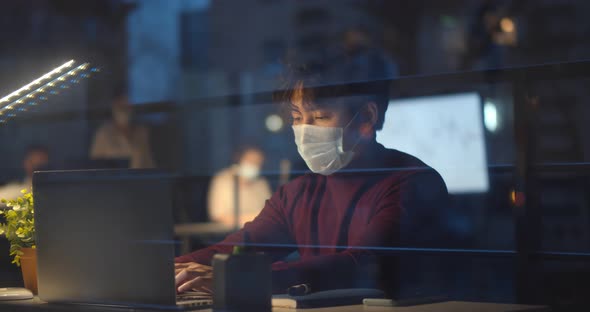 Portrait of Contemporary Asian Man Wearing Mask in Office While Working Late at Night