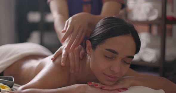 Young Attractive Brunette Woman Lying on Massage Table in Spa Center and Enjoying Rejuvenating Back