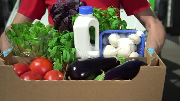 Closeup View of Man Courier Posing with Box of Organic Food in Hands During Working Day Spbd