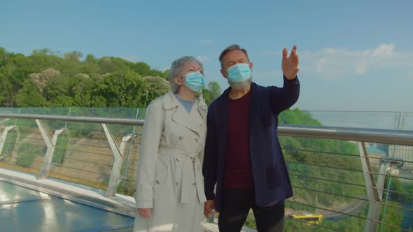 Senior Couple Walking in Park Wearing and Talking in Protective Masks