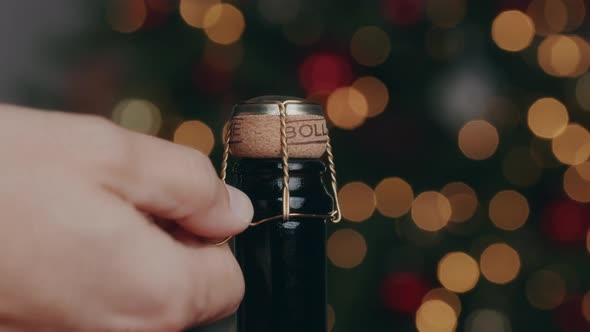 hand opens bottle of champagne for new year