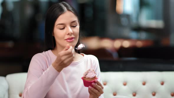 Woman Eating Cupcake with Whipped Cream Enjoying Delicious