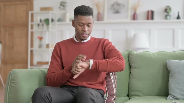 African Man Waiting while Checking Watch on Sofa