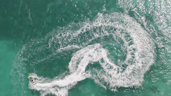 Aerial top view of jet ski or boat drawing a shape on sea ocean turquoise water. Adventure