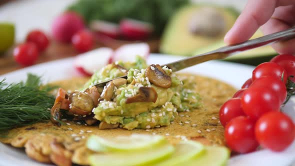 Spreading Avocado Smash On Chickpea Pancake. Healthy Vegan Omelette.